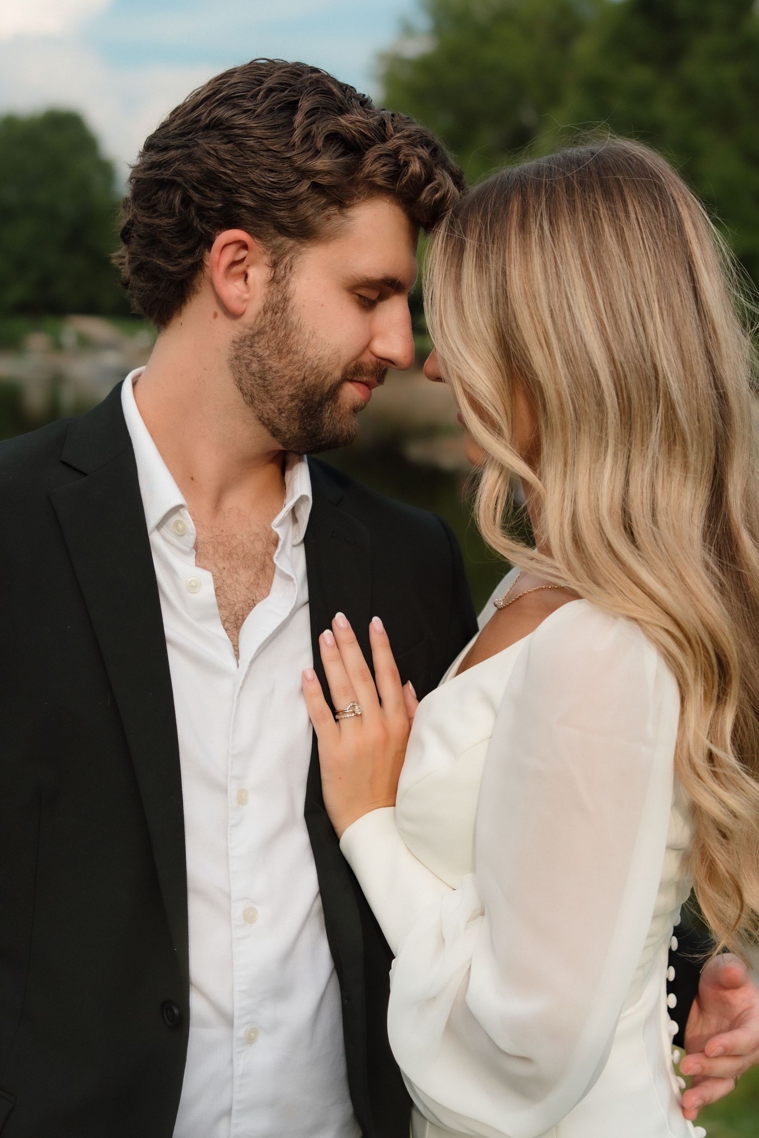 Romantic bride and groom nearly kissing in an intimate outdoor portrait with greenery background.