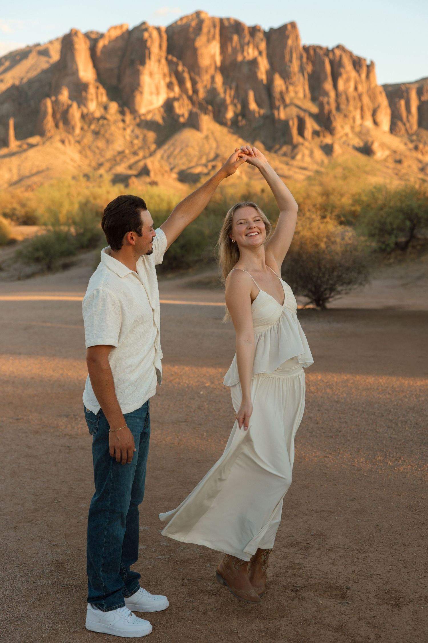 Couple dancing at golden hour in the desert with Superstition Mountains backdrop in Arizona.