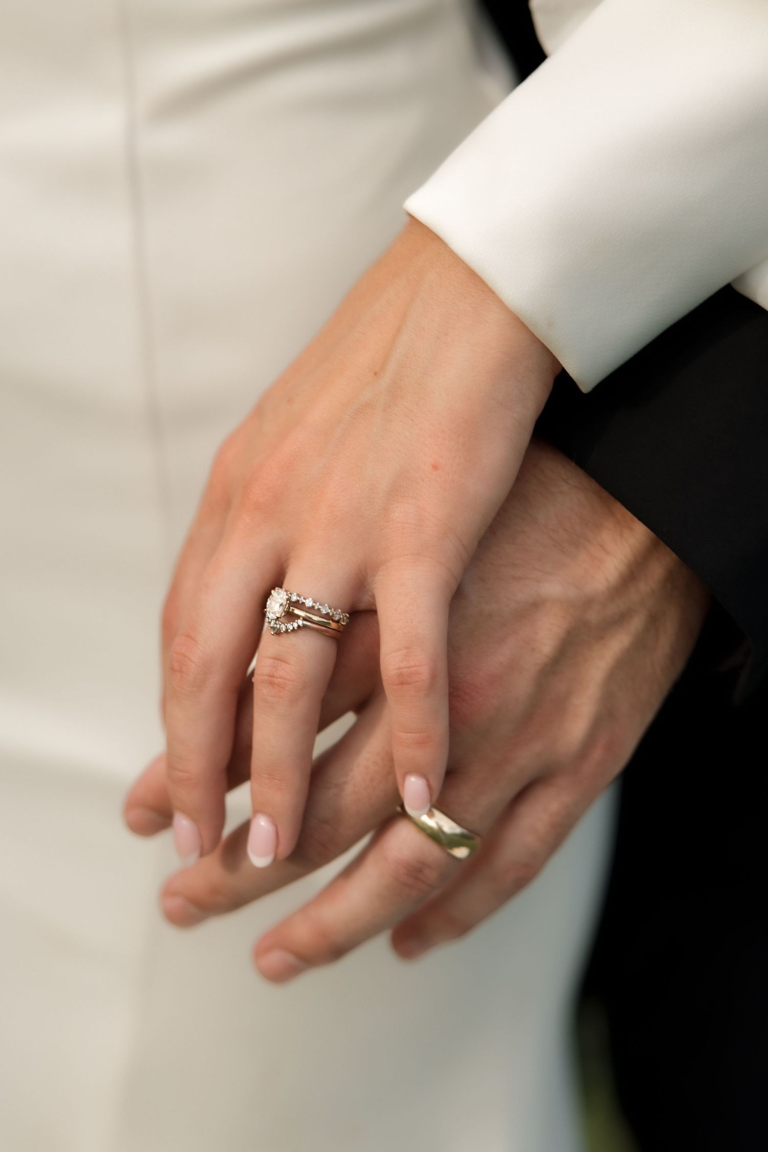 Close-up of bride and groom hands showing diamond engagement ring and gold wedding band.