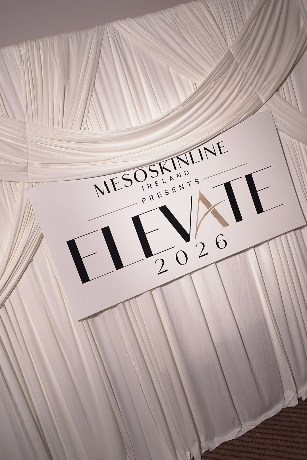 White draped backdrop with a sign reading Mesoskinline Ireland Presents Elevate 2026 at a skincare industry event.