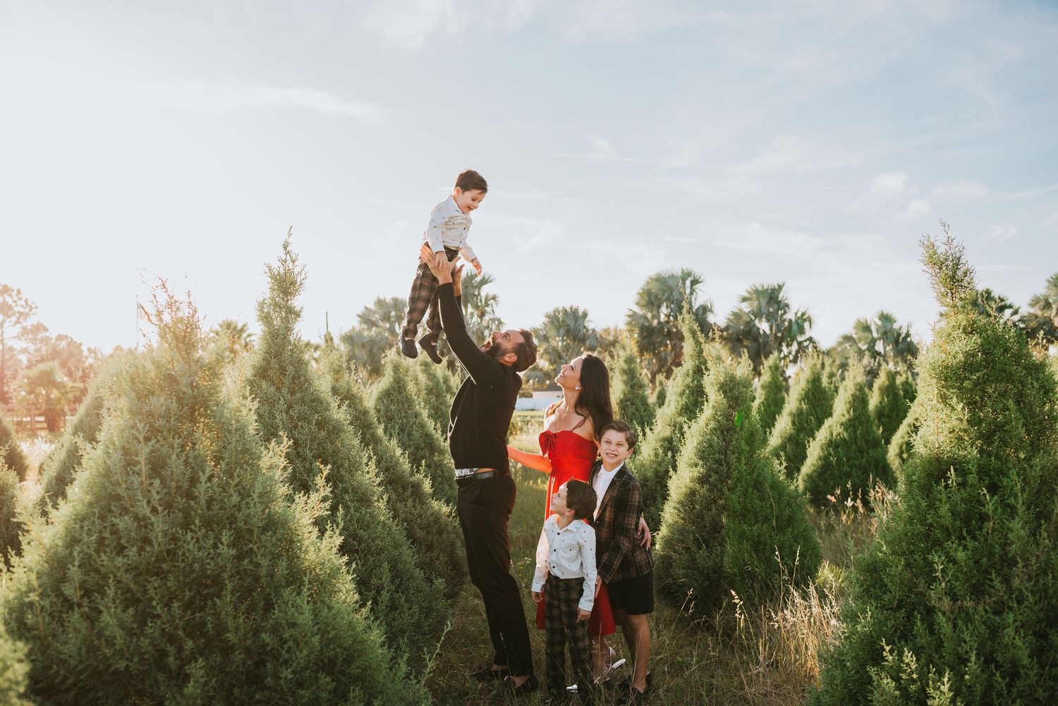 Family posing at a Christmas tree farm, during a holiday mini session at misty mountain tree farm