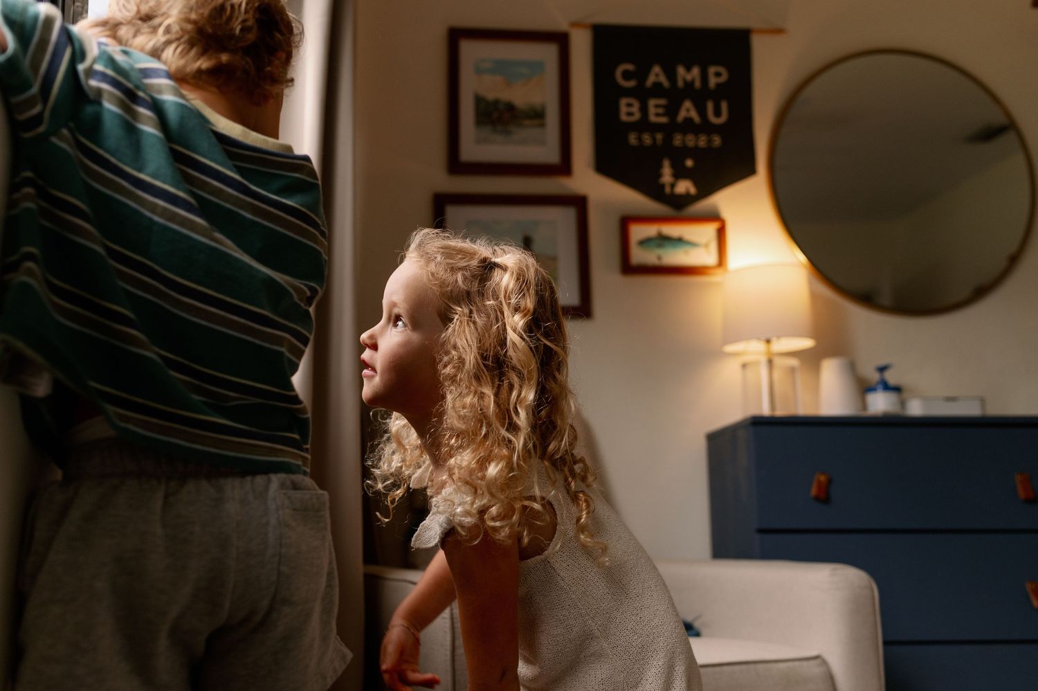 Two young children peek into a cozy bedroom during an in-home photo session in orlando fl