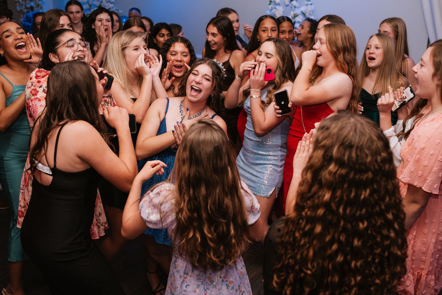 event photographer captures a large group of young women laughing and dancing together at a party in colorful dresses in orlando fl