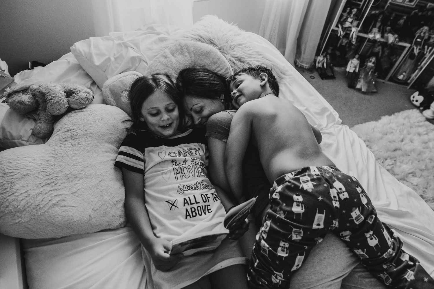 Black and white photo of two children laughing and cuddling together on a bed in cozy pajamas during an in-home photo shoot in lake Mary fl