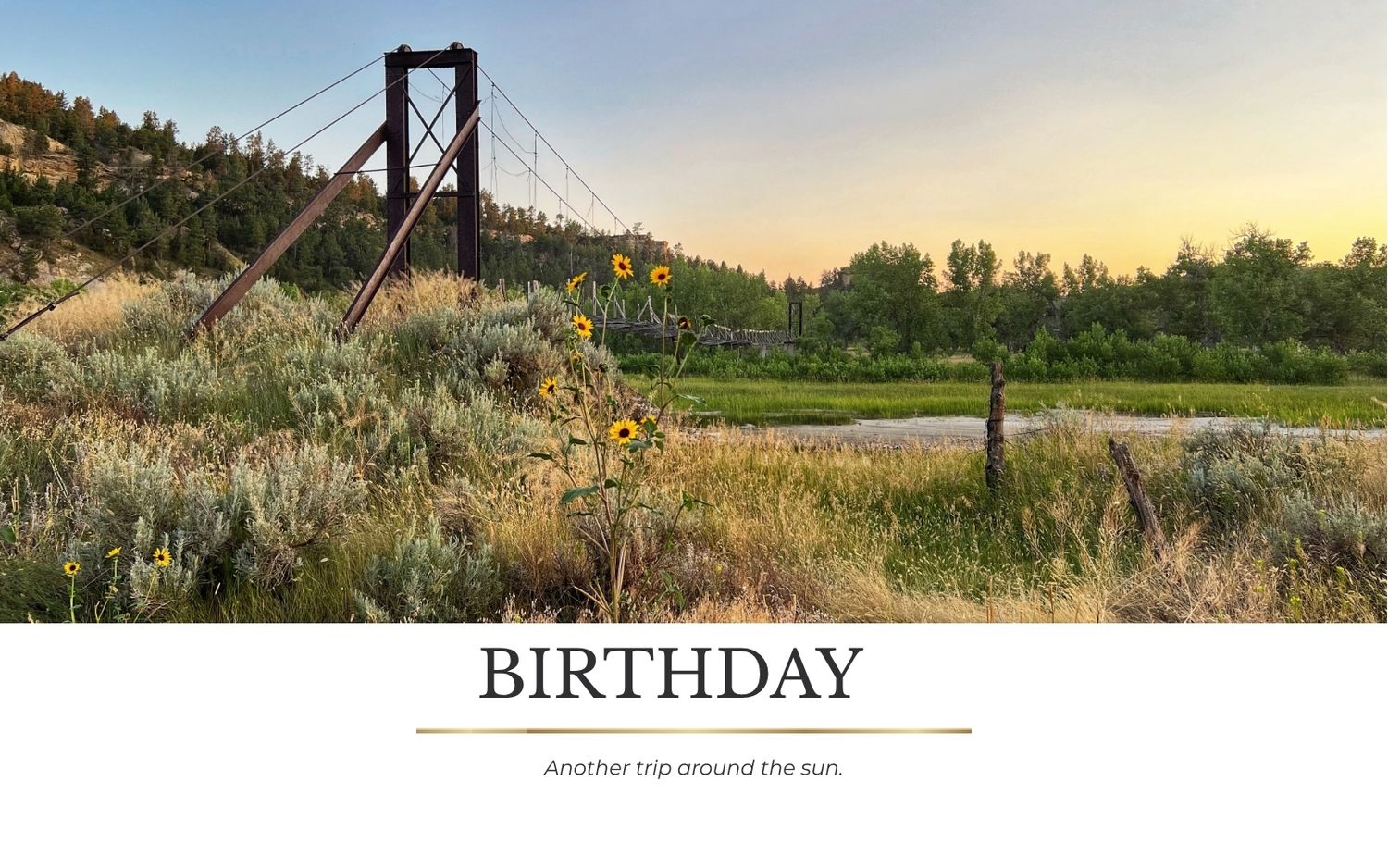 Birthday card featuring a scenic suspension bridge at sunset with sunflowers and lush greenery in a peaceful valley.