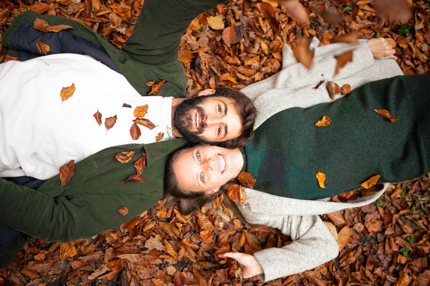 Couple d'amoureux qui jouent avec des feuilles d'automne pour leur séance engagement dans les yvelines