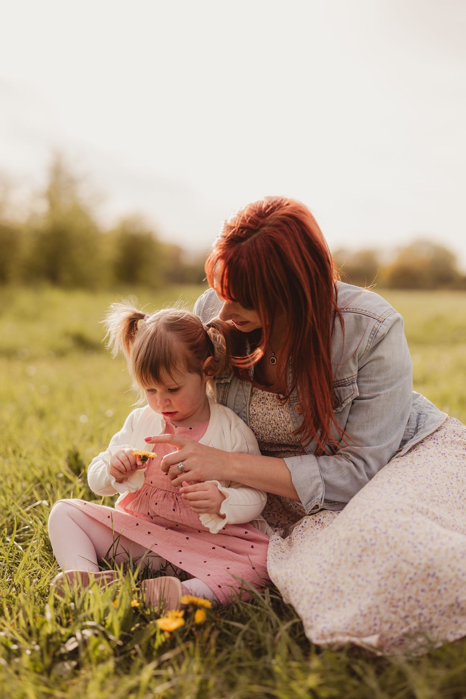 Candid moment of a mum and daughter picking daisies in a field; natural family photography in Stoke Gifford by a mobile photographer.