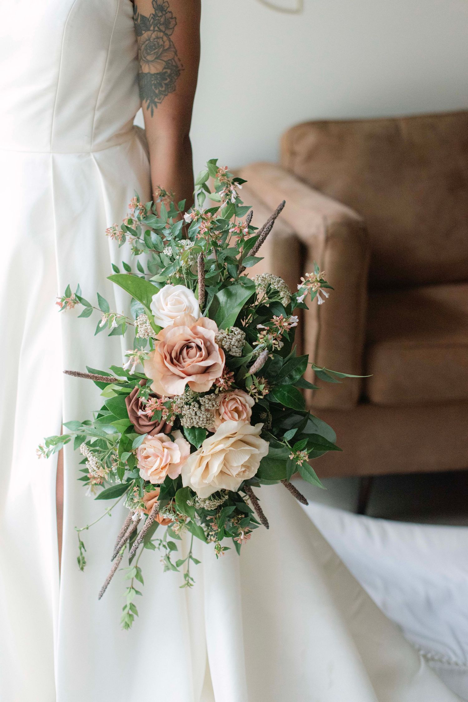 Delicate pink roses and greenery bouquet arranged with eucalyptus against a light background.