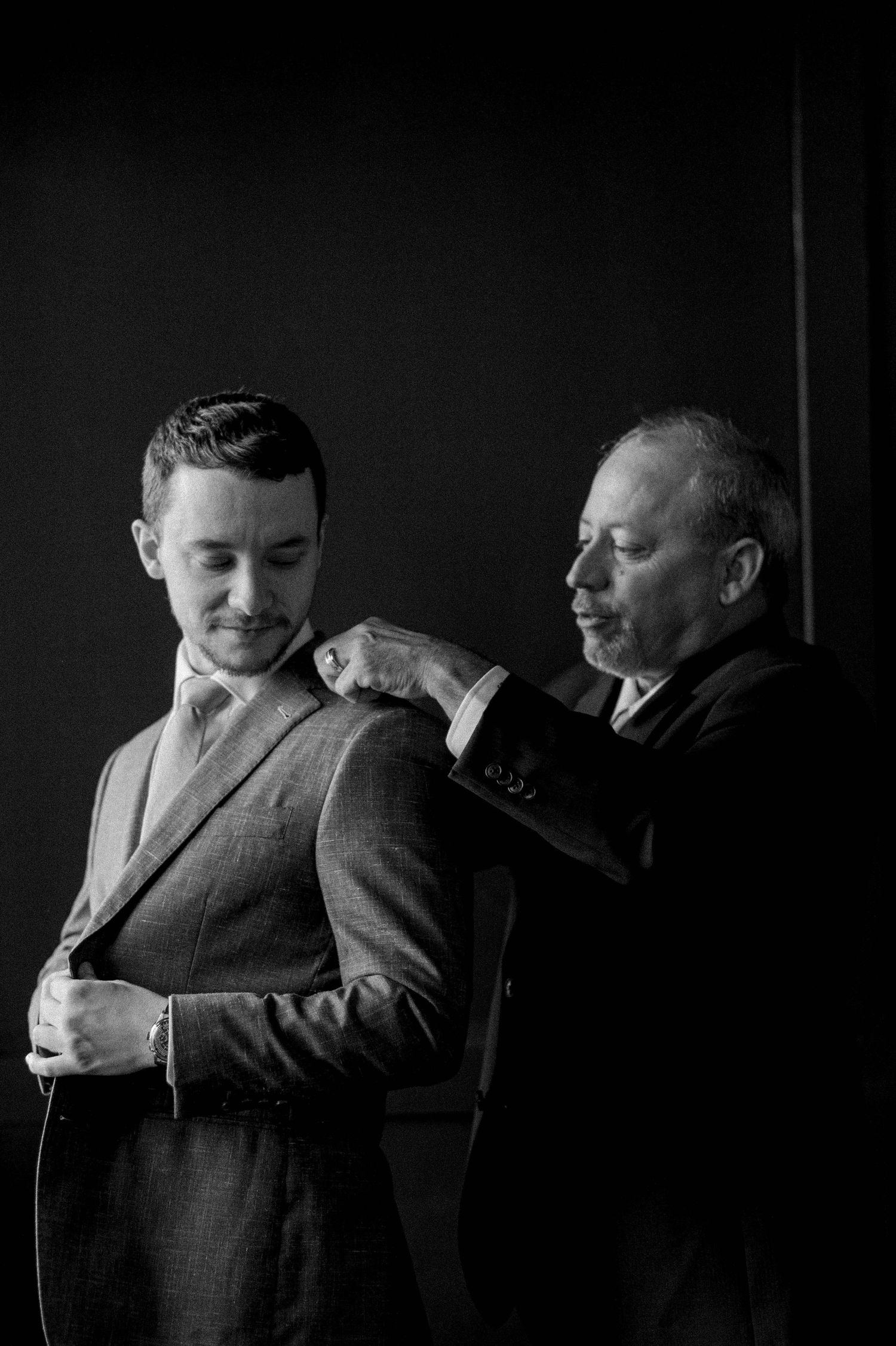 Emotional black and white photos capture tender moments between men in formal attire.
