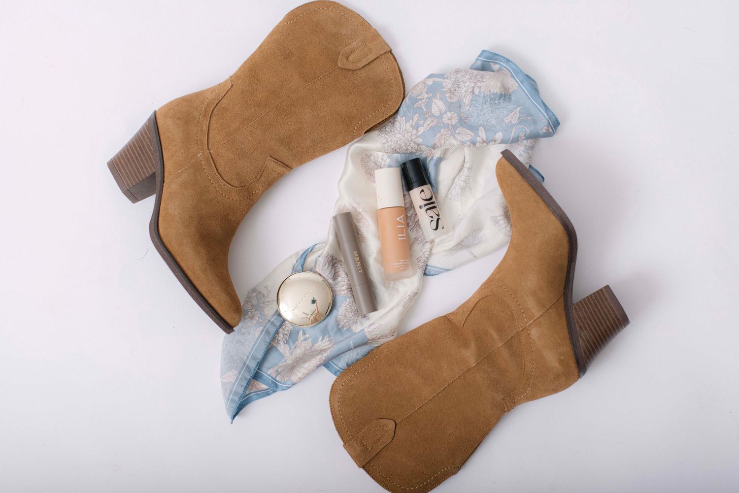 Flat lay of tan suede boots with white clothing items against light background.