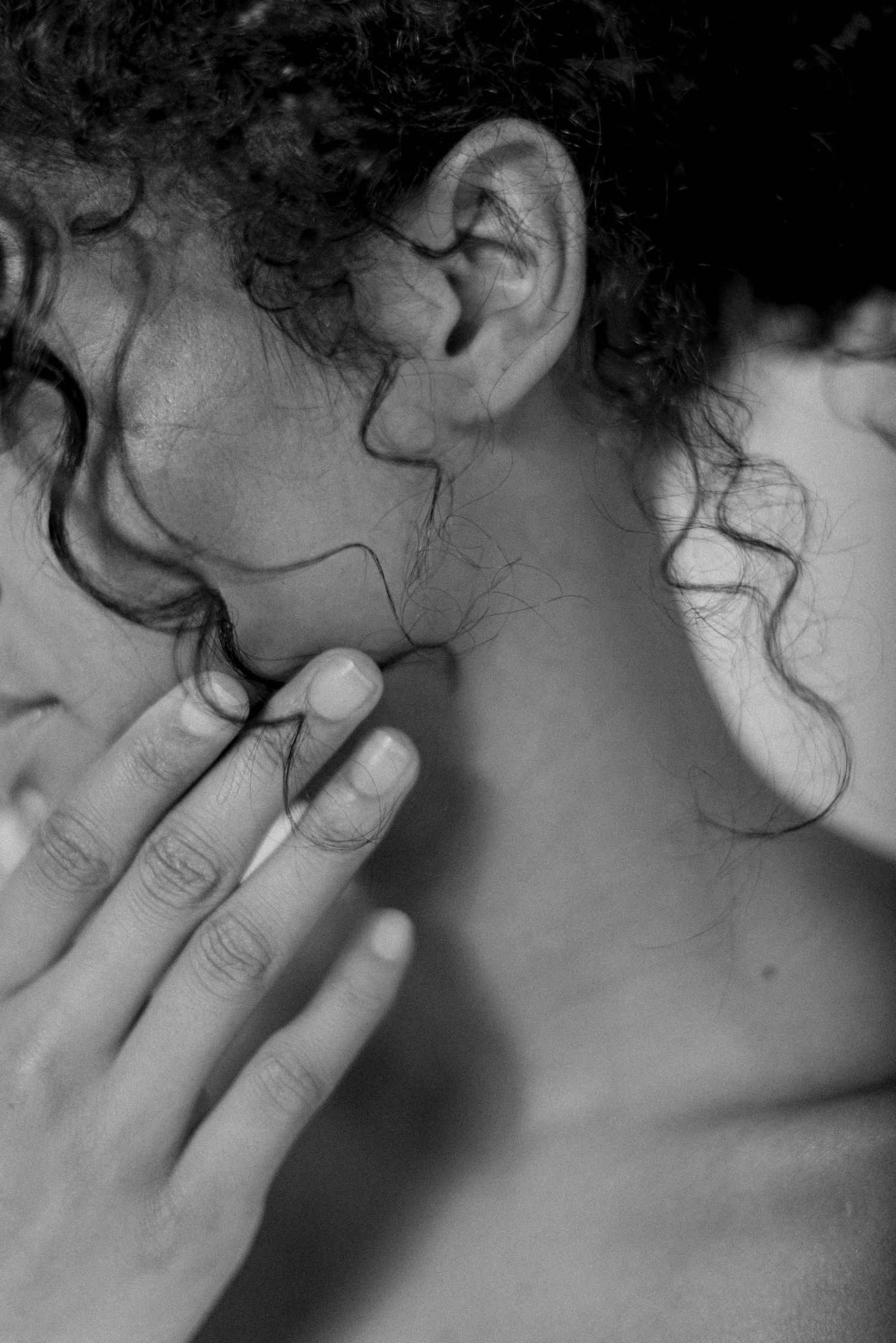Close-up profile view showing neck and hand in dramatic black and white lighting.