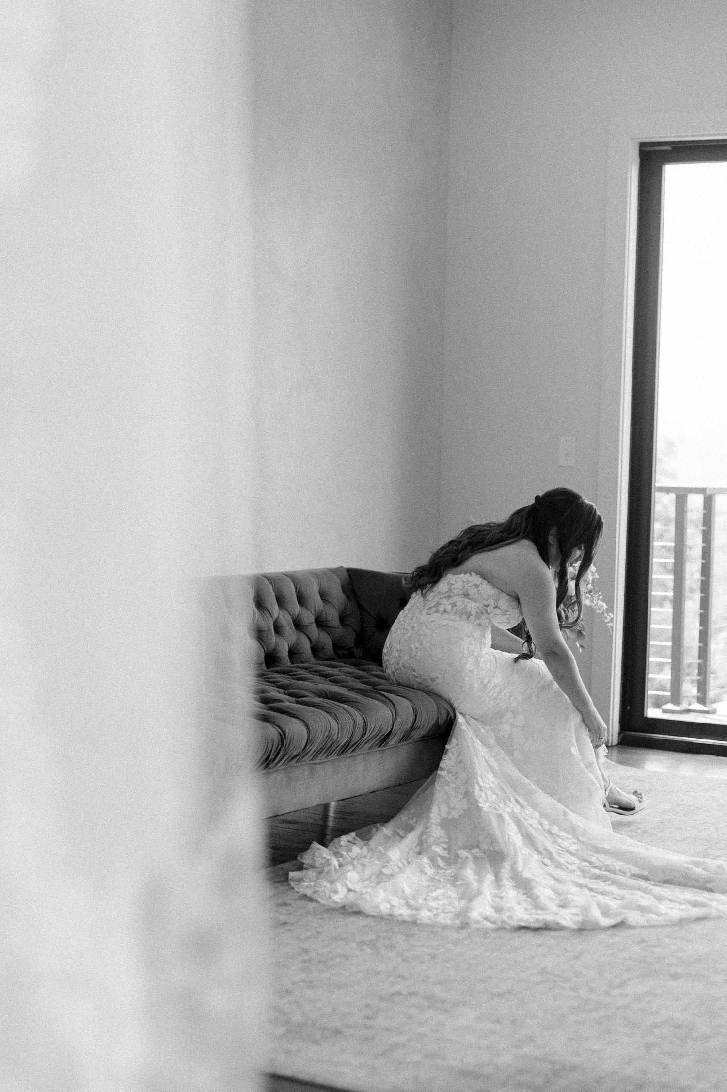 Wedding dress with intricate lace details spreads across a minimalist room with window views.