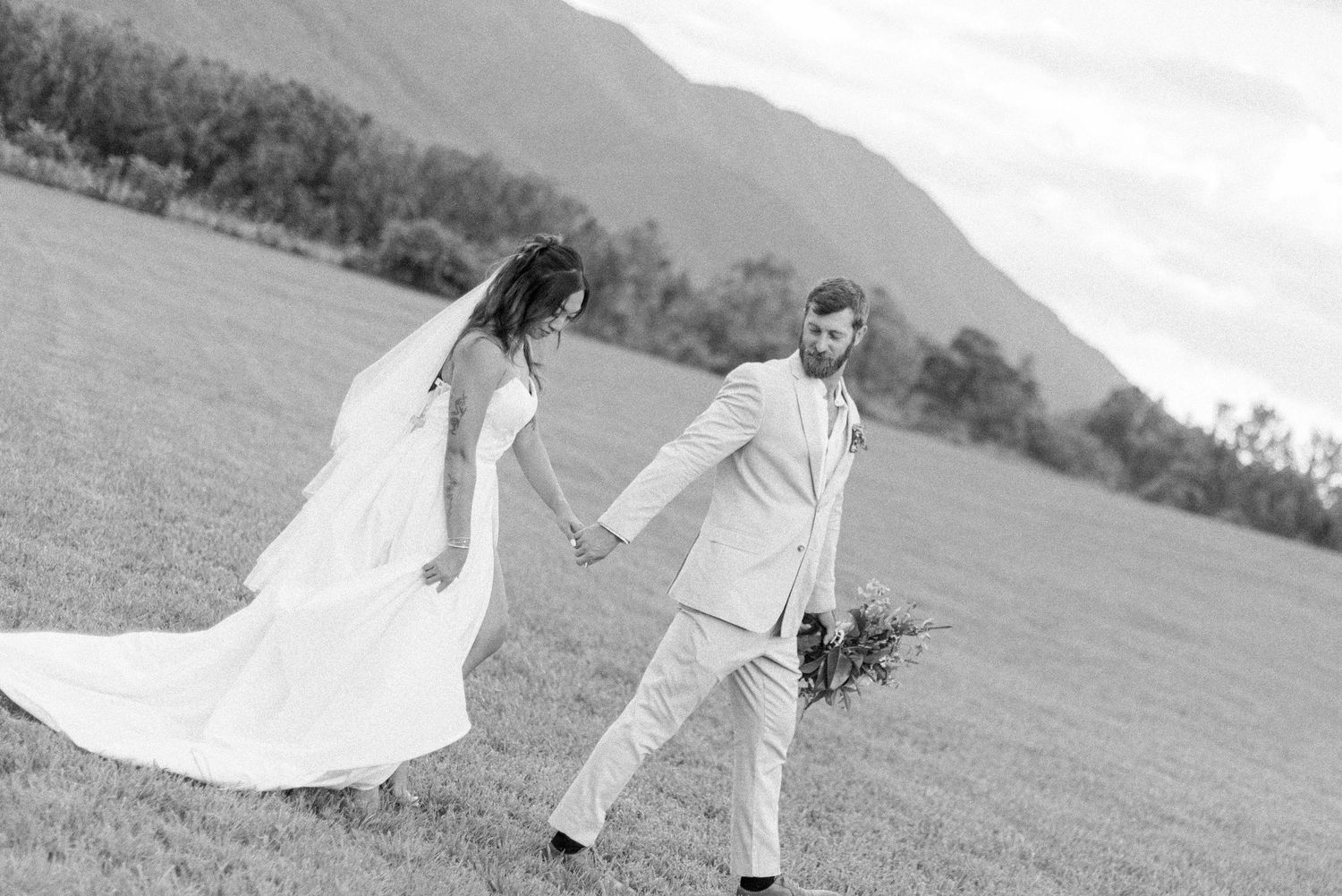 A romantic black and white photo series showing a couple dancing in an open field with a flowing white dress.