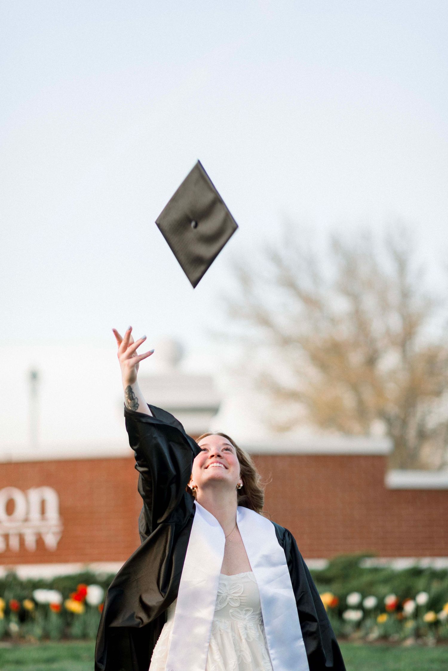Graduate tossing mortarboard cap in the air with joy.