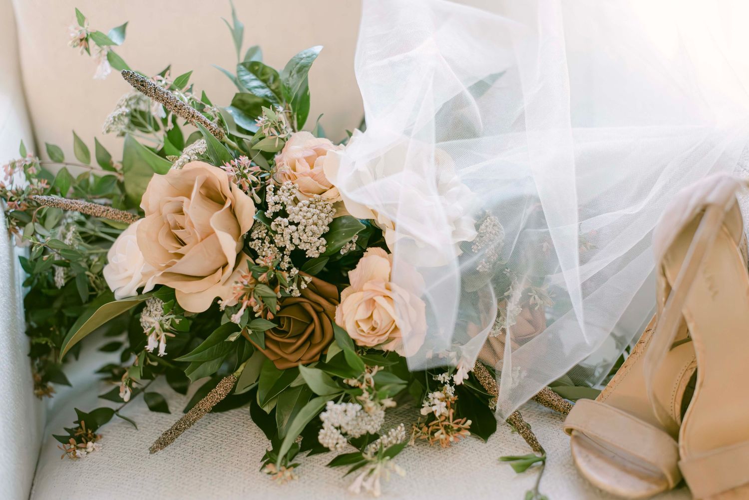 A collection of delicate wedding floral arrangements with peach roses and greenery displayed against a light beige background.