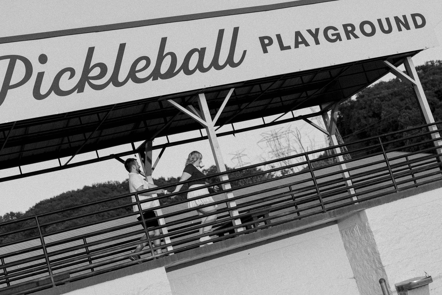 A black and white sign for a pickleball playground hangs overhead in an indoor sports facility.
