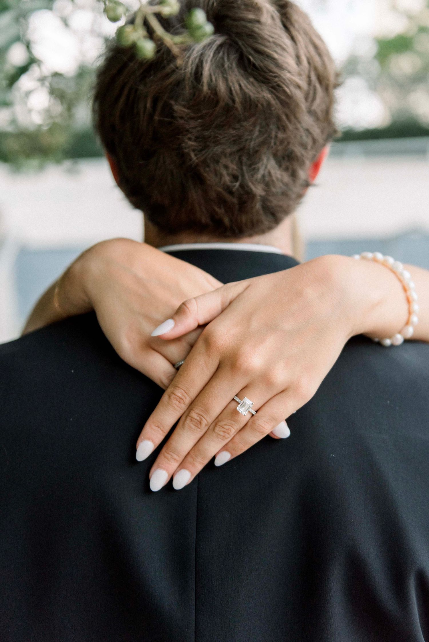 A series of intimate engagement photos showing hands with a diamond ring embracing across a black suit jacket in Knoxville TN