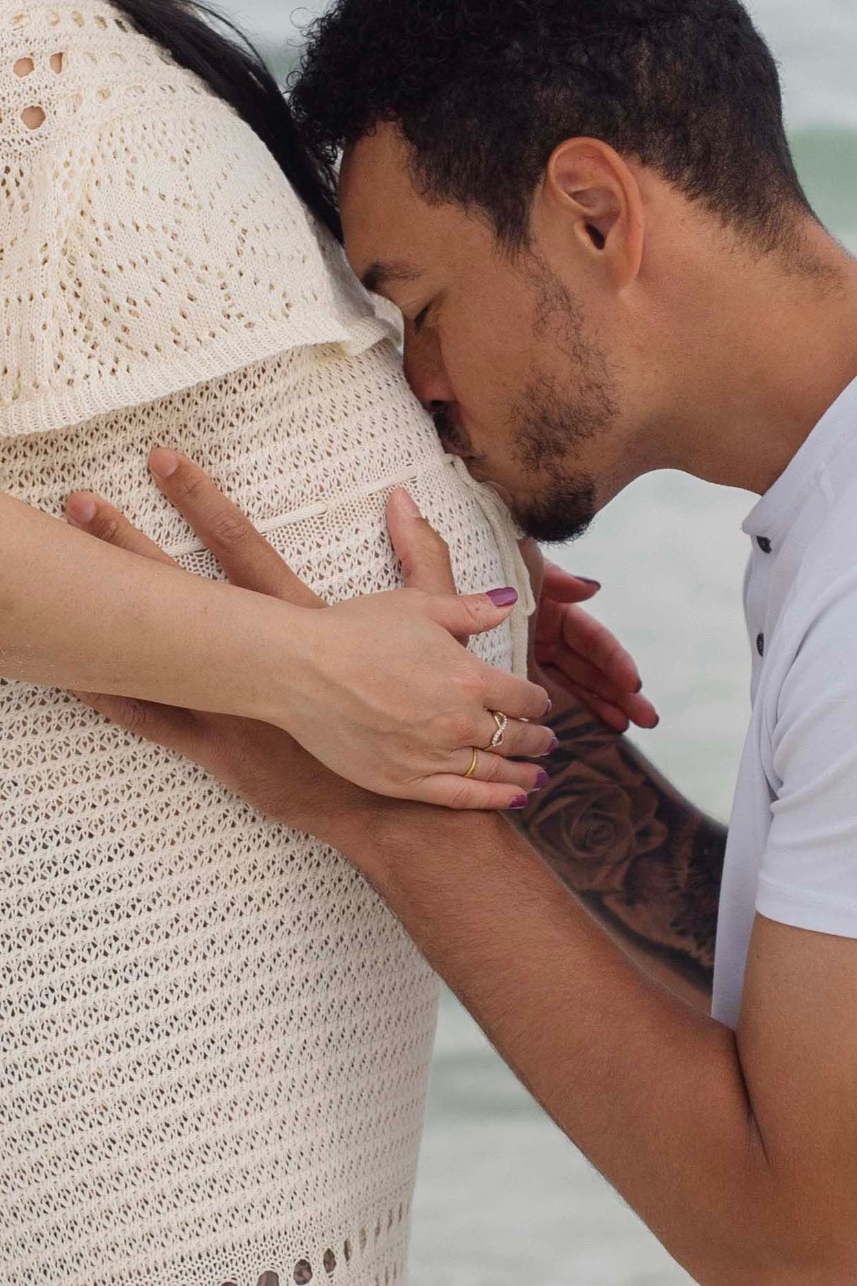 A sequence of tender moments showing someone kissing a pregnant belly in white lace dress against a light background.
