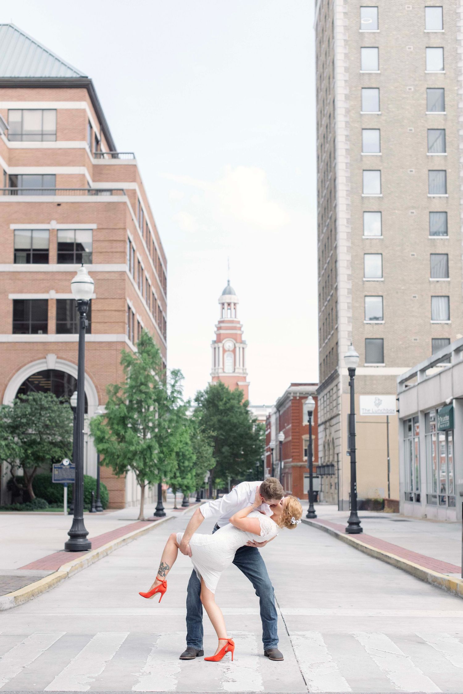 Urban wedding photo shoot on a city street with brick buildings and lamp posts in the background.