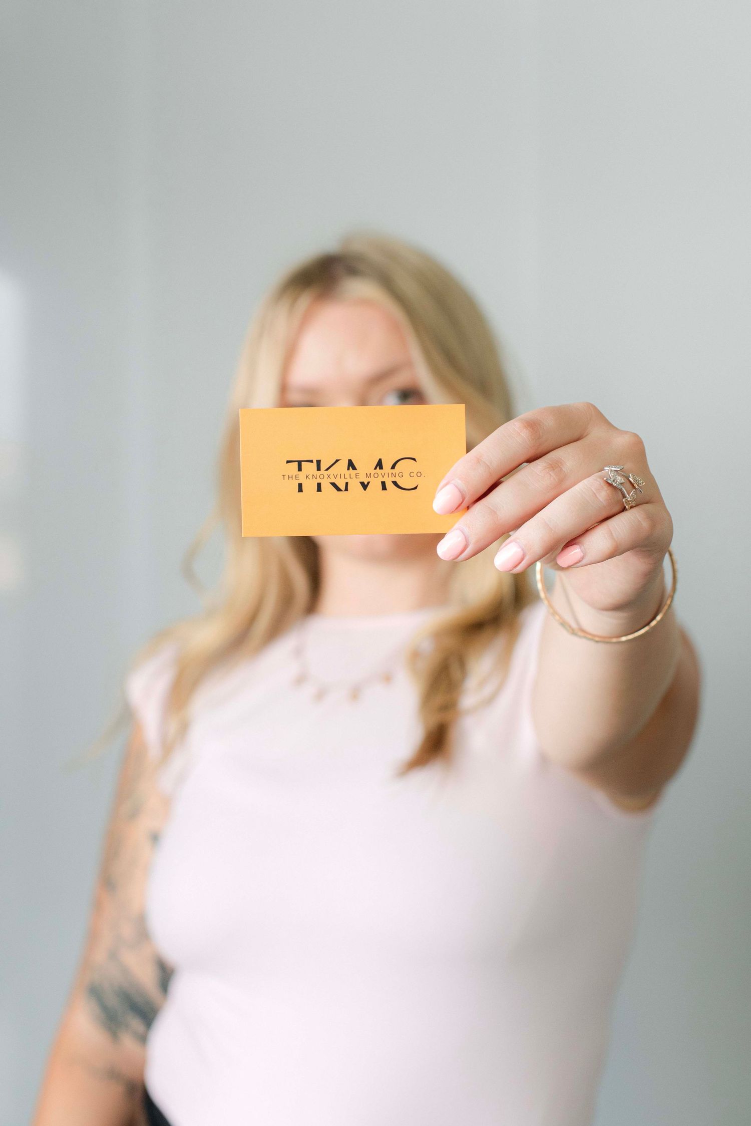 Person holding up an orange card against a light background in a sequence of artistic shots.
