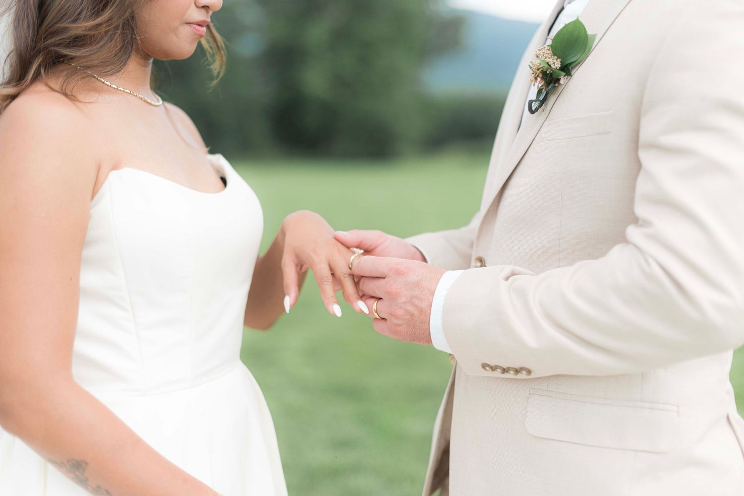 A couple holds hands during an outdoor wedding ceremony in a lush green garden setting.