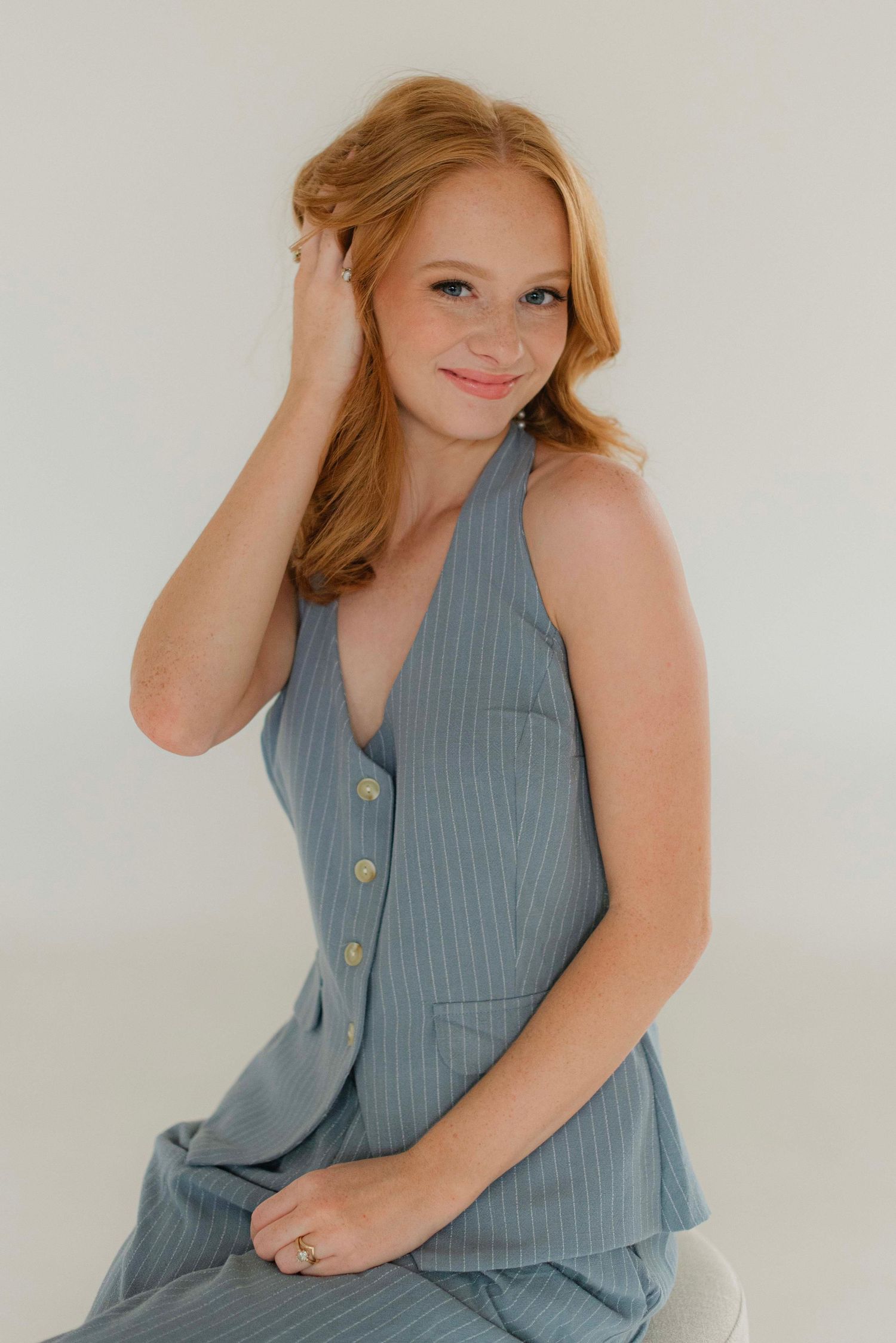 Person in a blue sleeveless dress posing against a white studio backdrop.
