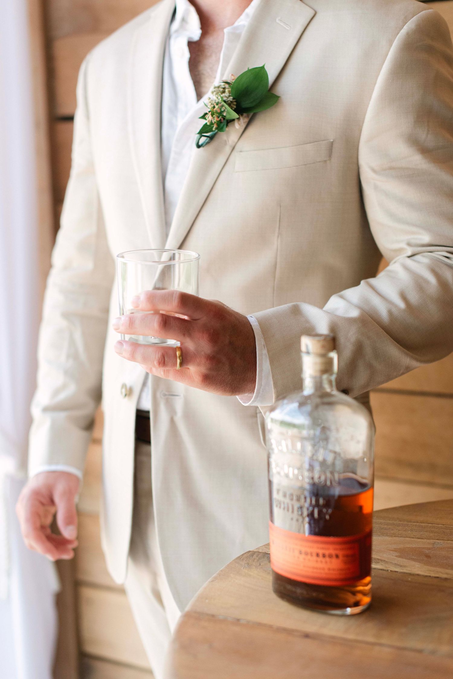 A sequence of images showing hands in a cream suit pouring and holding a glass of amber-colored liquor.
