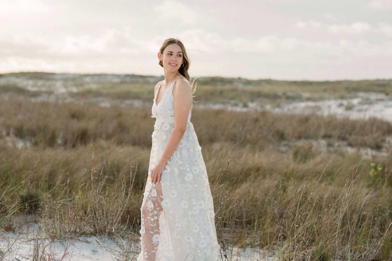 A light blue lace dress flows in the coastal breeze against a scenic beach backdrop.
