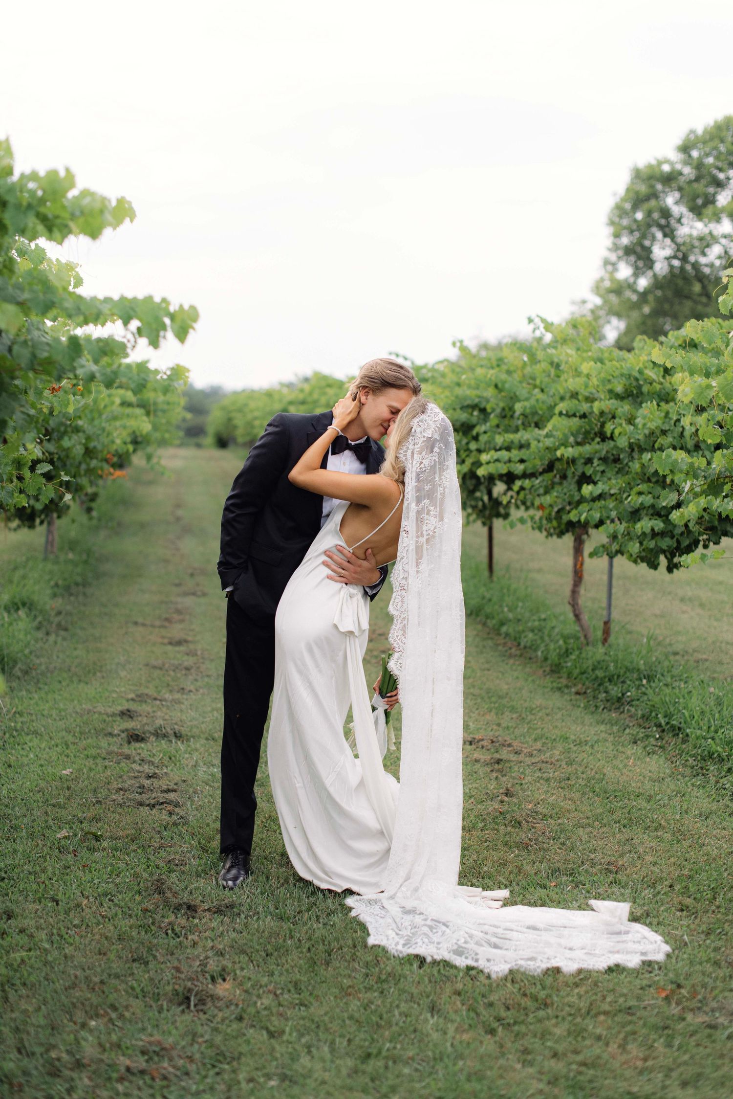 Romantic couple shares intimate moments among vineyard rows during a wedding photoshoot.