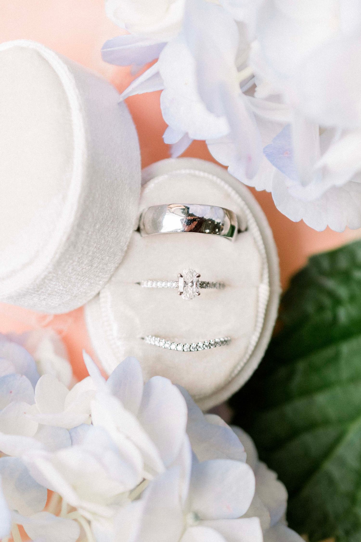 Wedding rings displayed elegantly among white floral arrangements and soft lighting.
