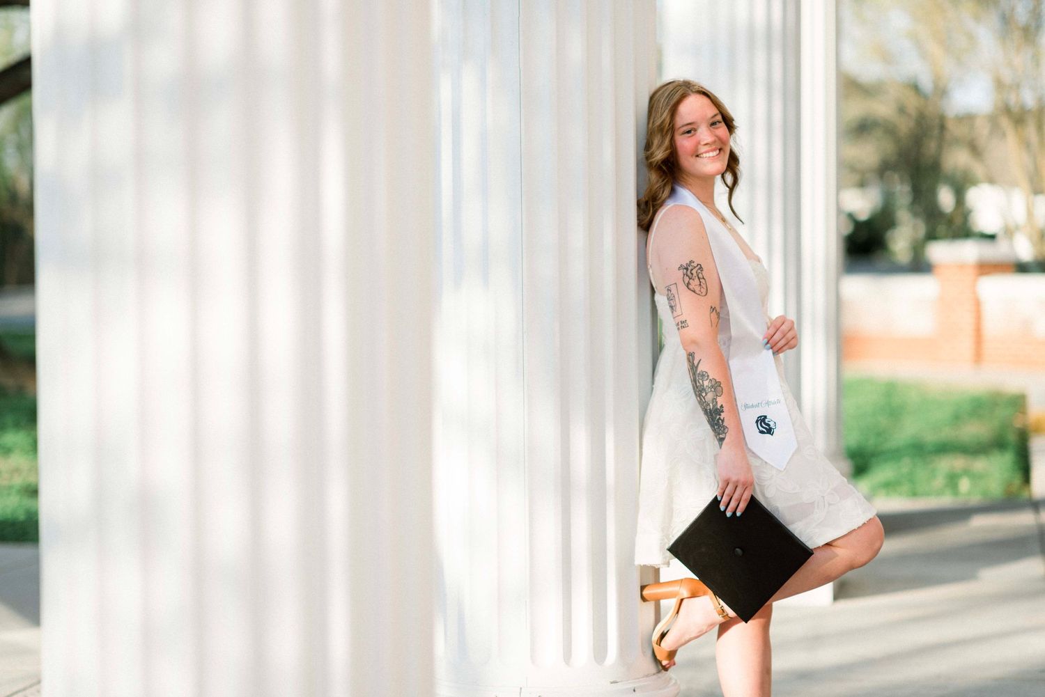 Maternity photos captured against white columns in natural lighting.