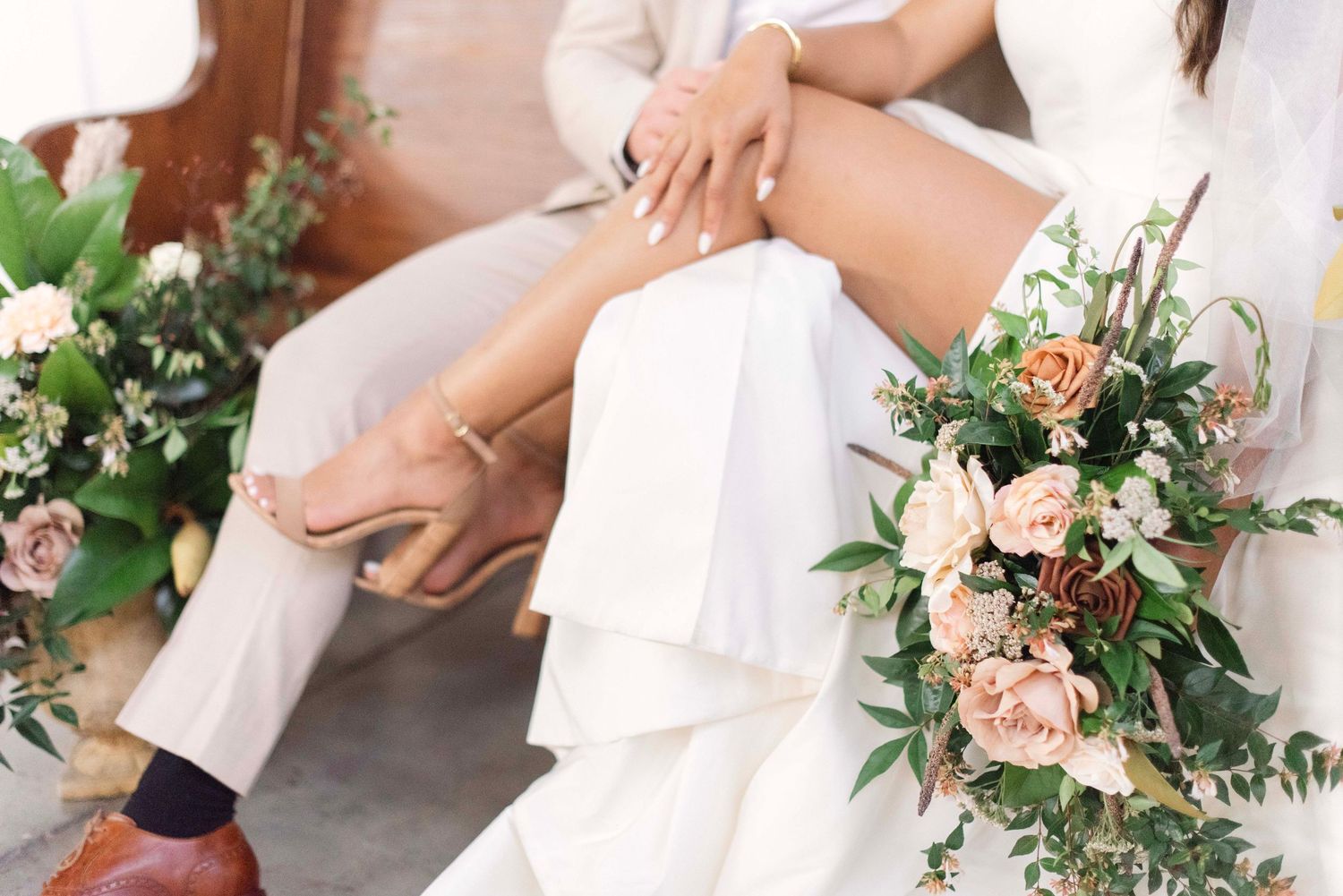 A bride in a white dress holds a romantic pink and white floral bouquet with cascading greenery.