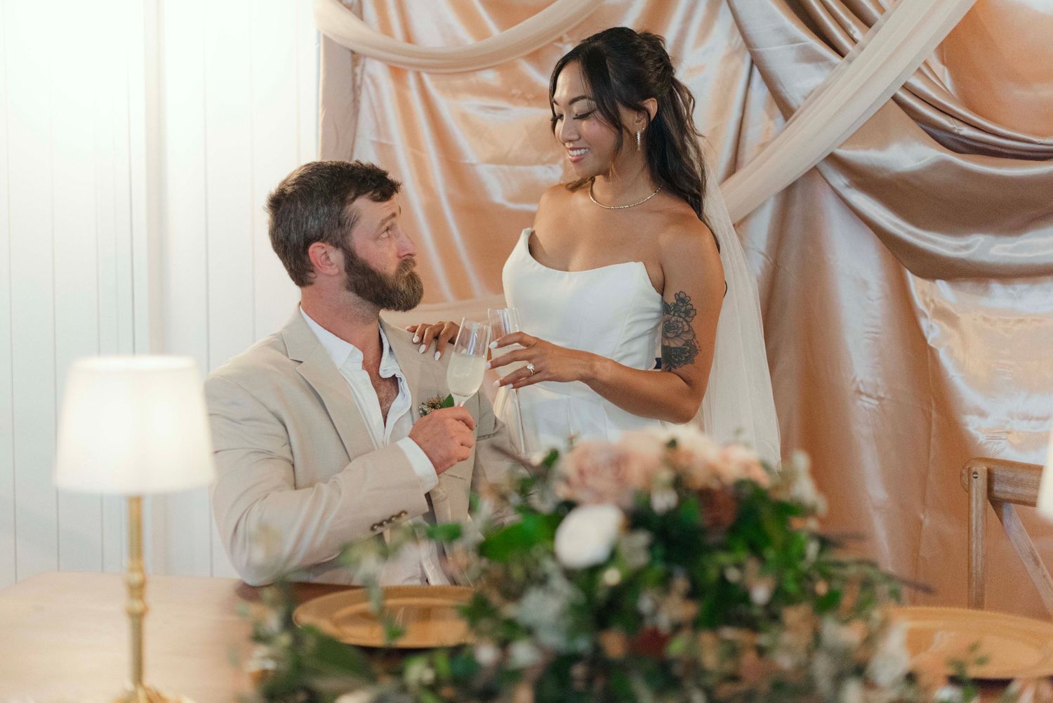 Couple shares an intimate moment during their wedding reception under elegant draped fabric decor and soft lighting.