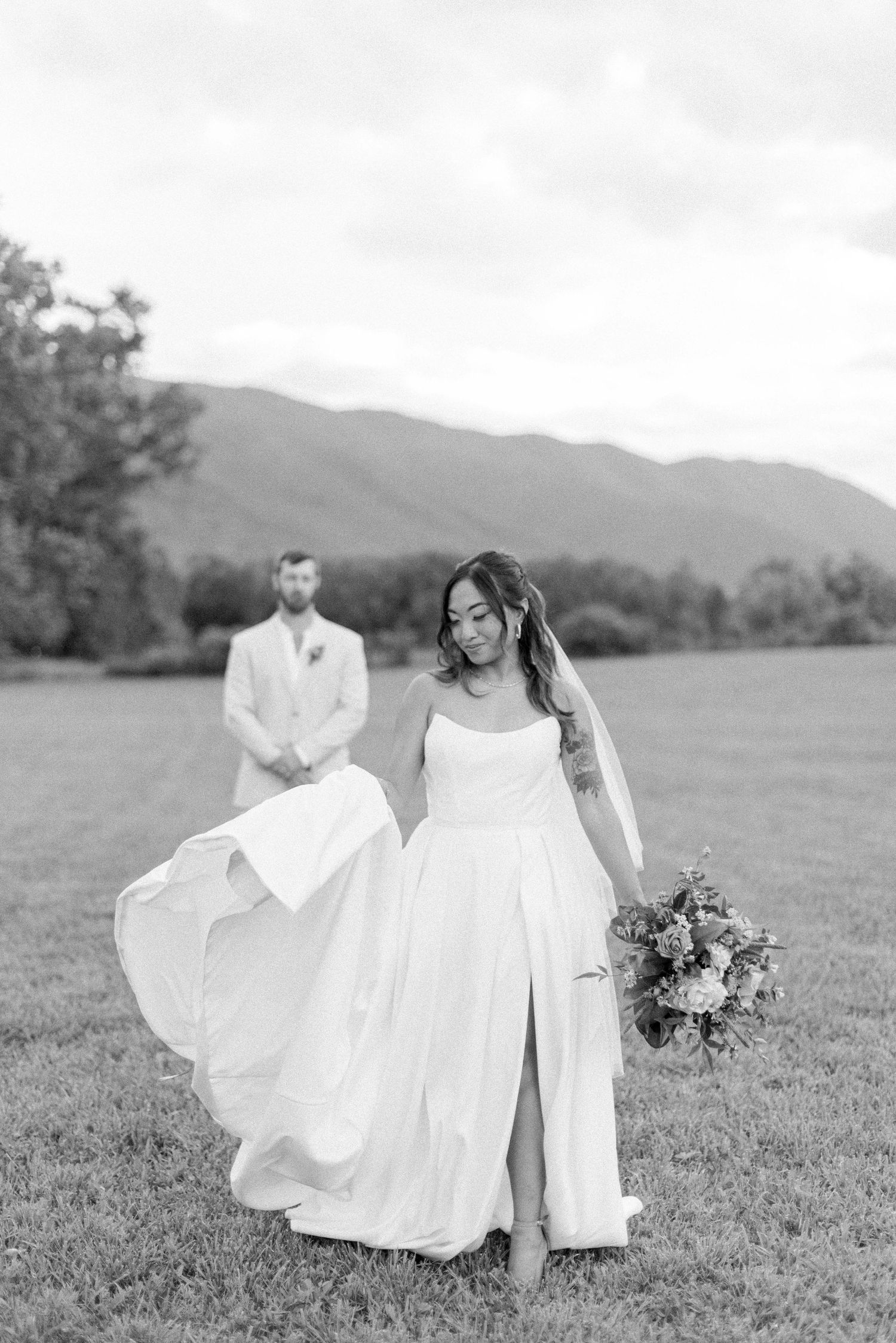 A romantic black and white wedding photo series showing a flowing white dress billowing in the wind on a grassy hillside.