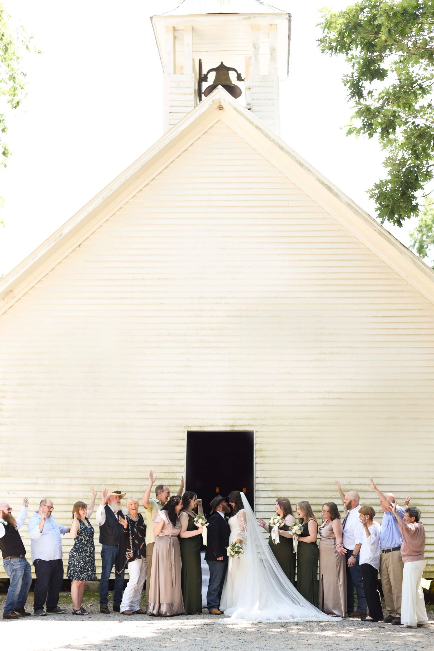 Wedding ceremony outside a white chapel with guests lined up along the entrance.