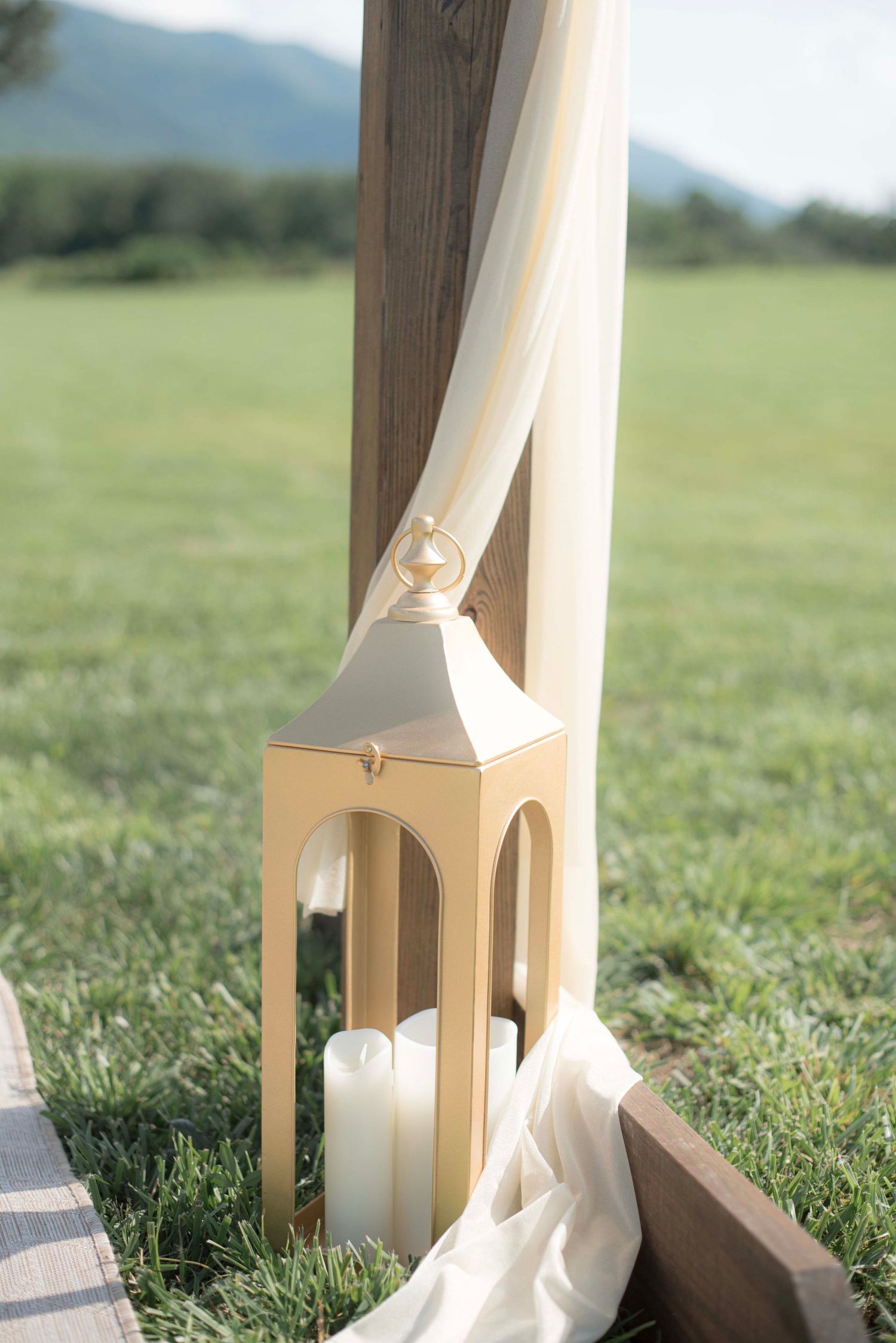 White fabric draping and decorative lanterns create an elegant outdoor wedding setting on grassy field.