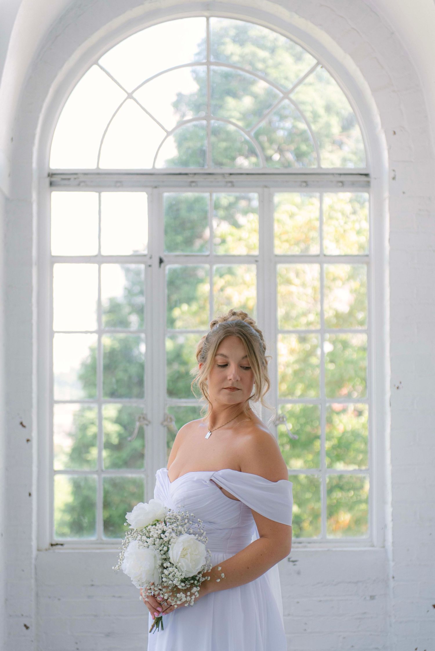 Elegant bridal portrait in a bright white room with arched windows and natural light.