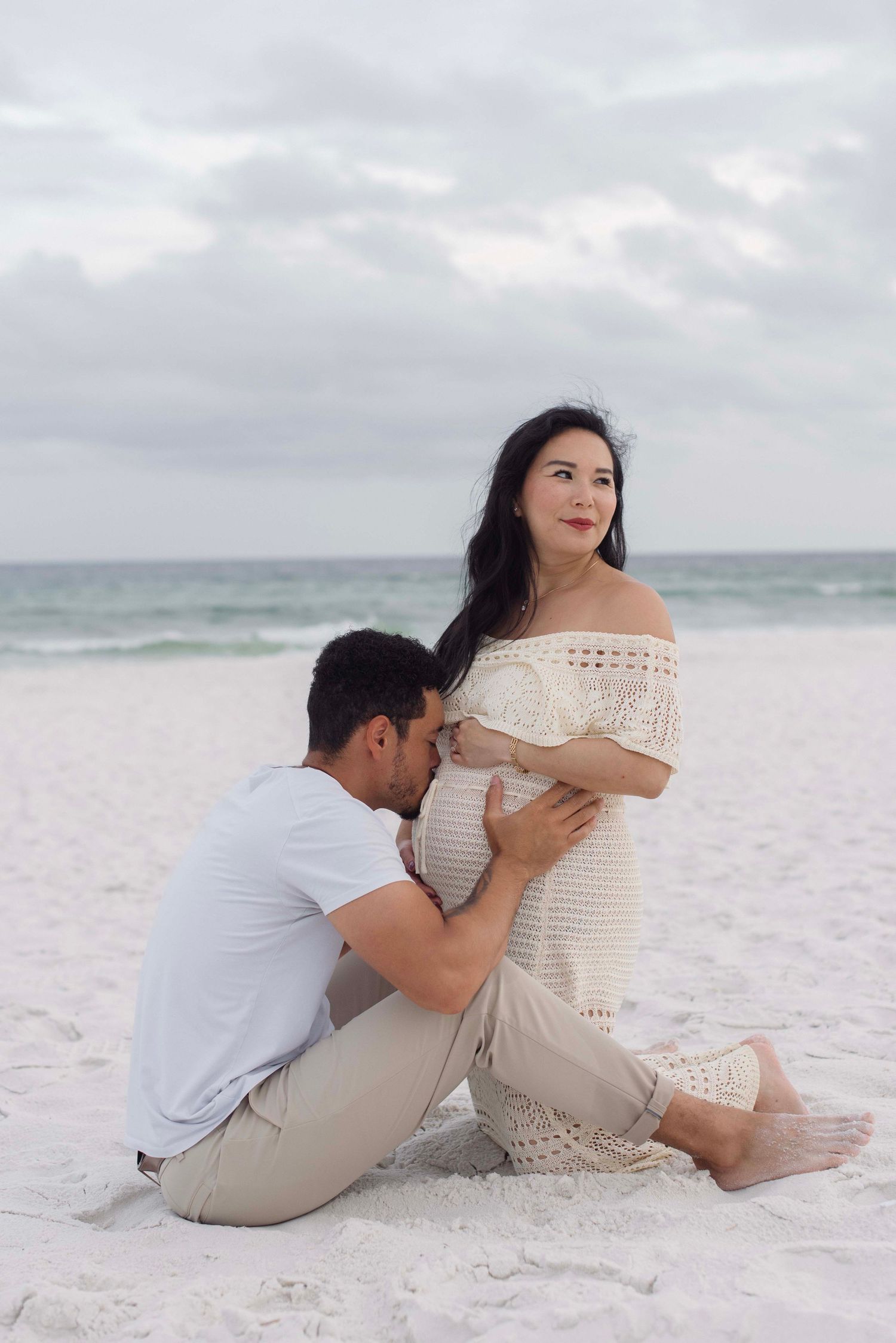 A romantic couple poses on a white sandy beach for engagement photos in a series of connected shots.