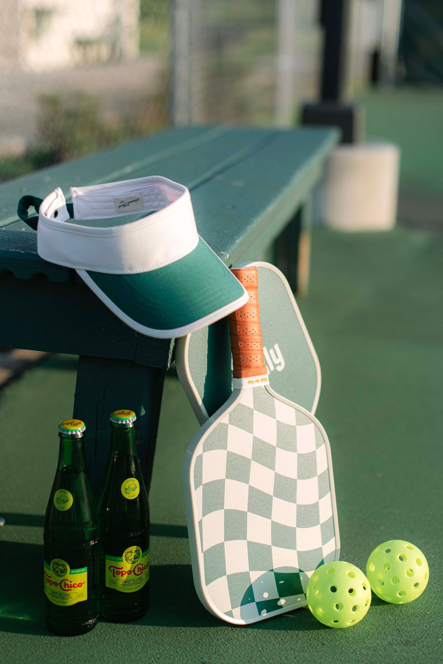 A sequence of four similar shots showing pickleball paddles and balls with green beer bottles on a court surface.