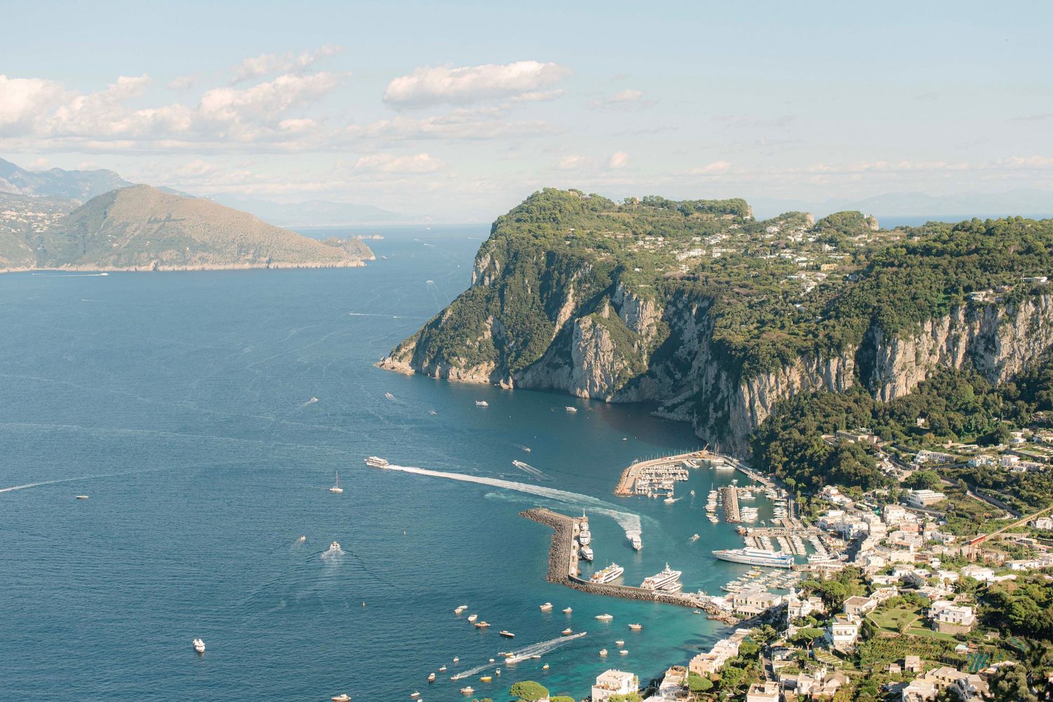 Panoramic aerial view of the Amalfi Coast in Italy showing dramatic cliffs, blue Mediterranean waters and coastal towns.