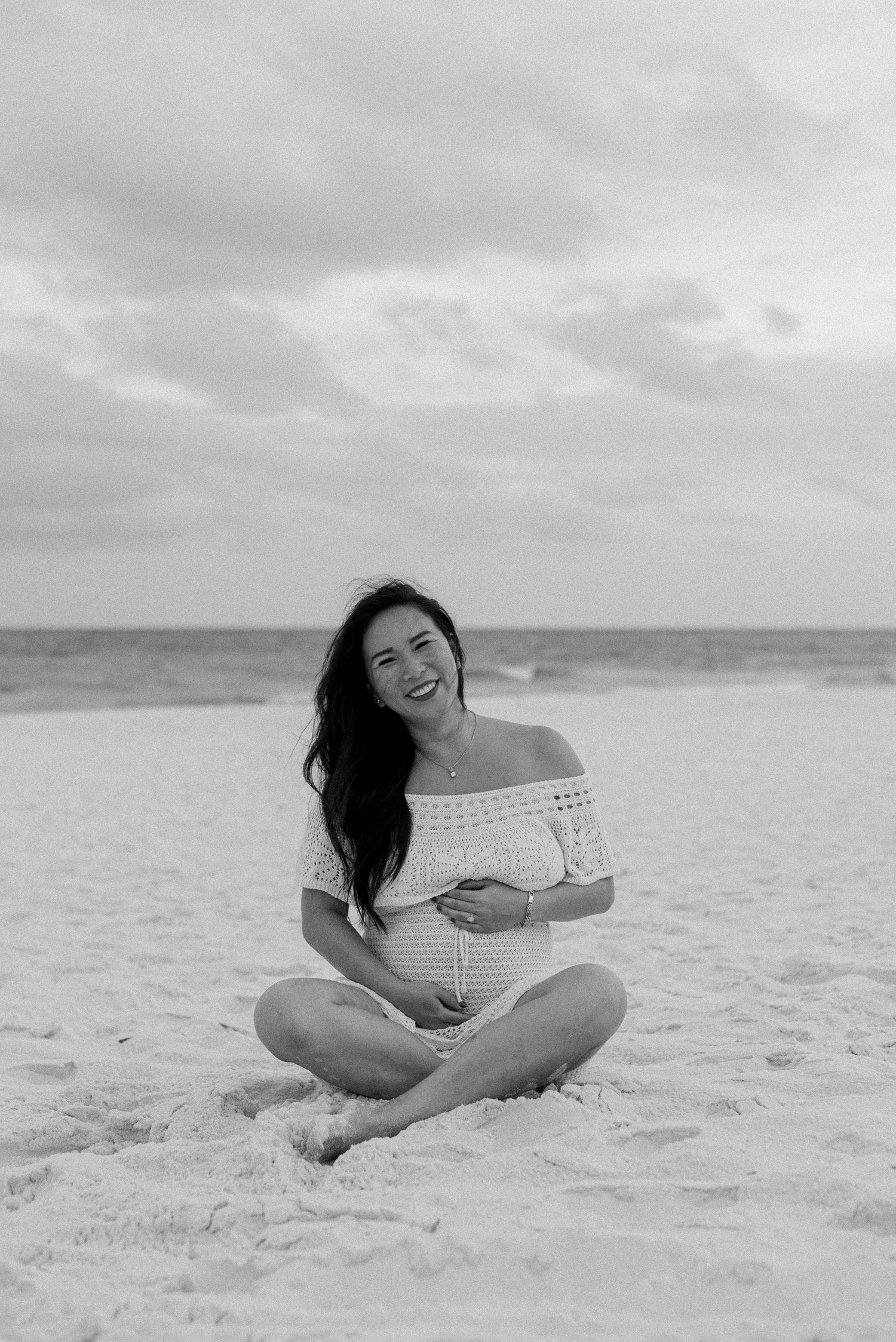 A series of black and white photos showing someone reclining on a sandy beach by the ocean.
