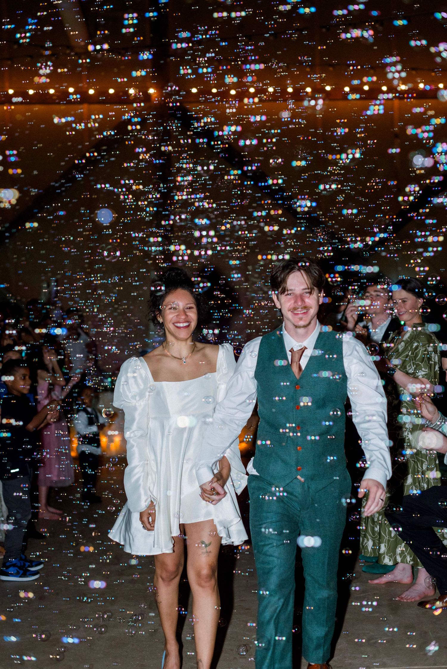 Newlyweds exit their reception through a shower of confetti and sparkles.
