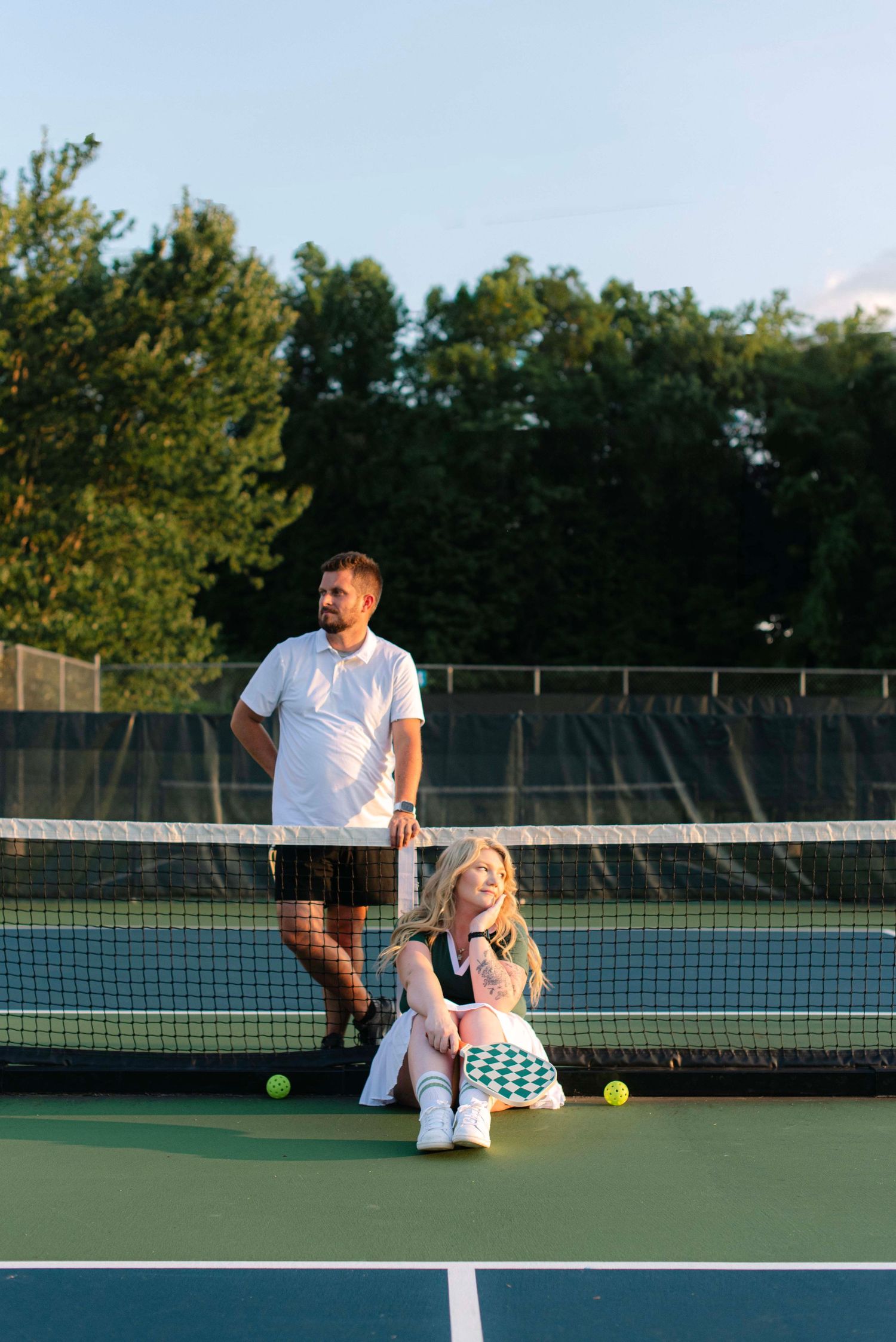 Tennis instructor teaches student proper form during private lesson on outdoor tennis court at sunset.