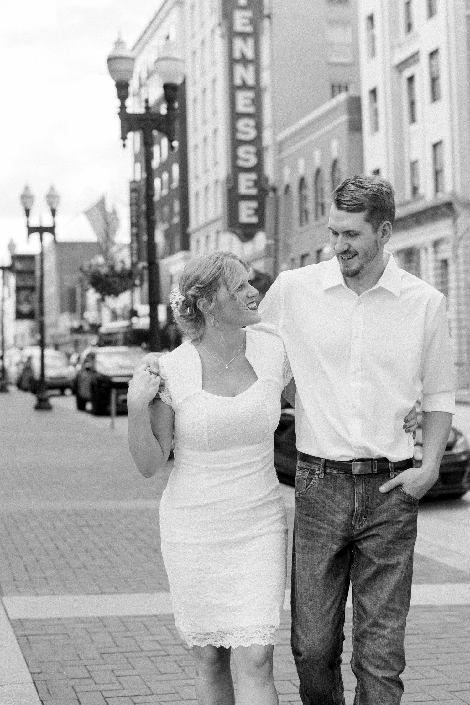 Couple walking and laughing together on a brick sidewalk in downtown area.