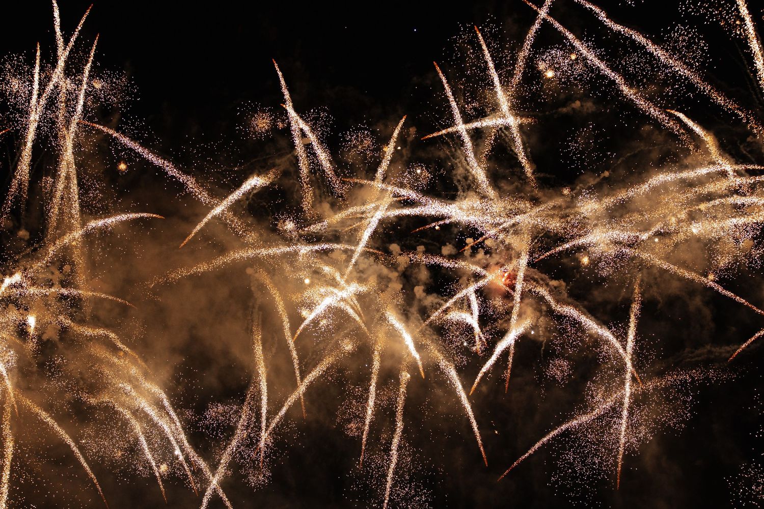 Golden sparklers create a magical display of light trails and sparks against a dark background.