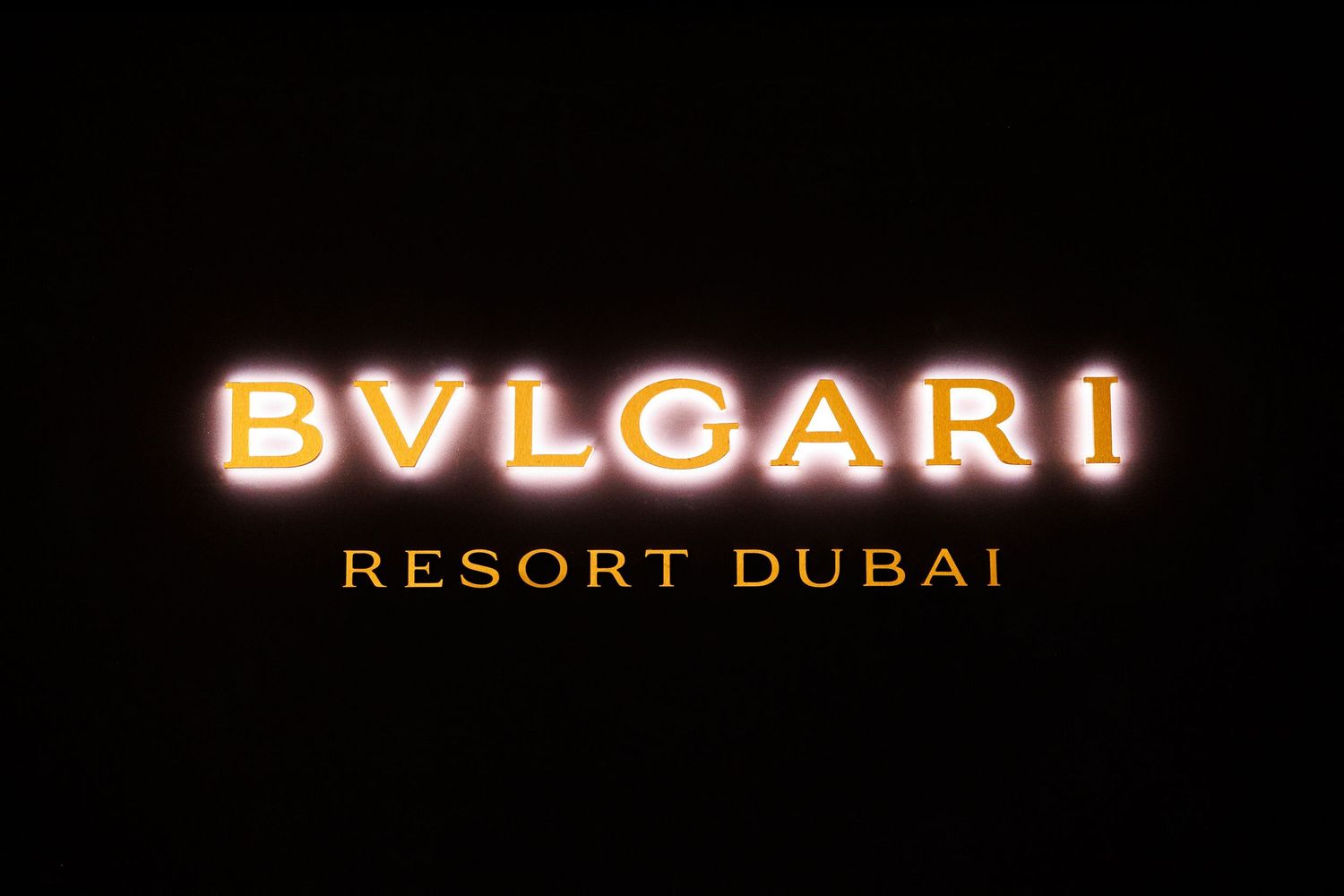 Illuminated BVLGARI Resort Dubai logo sign glowing against dark background at night.