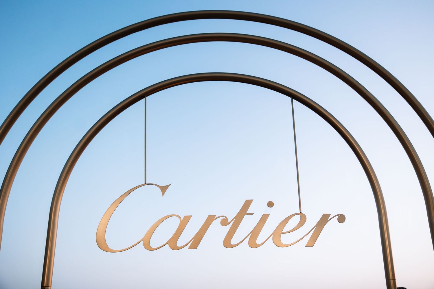 Four golden Cartier logos displayed in a row against a white background.
