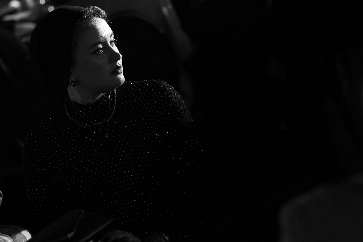 A black and white photograph shows a person in silhouette against a dark background with dramatic lighting.