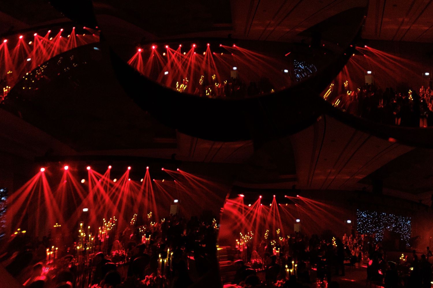 Concert venue with dramatic red lighting arrays creating geometric patterns across the ceiling.