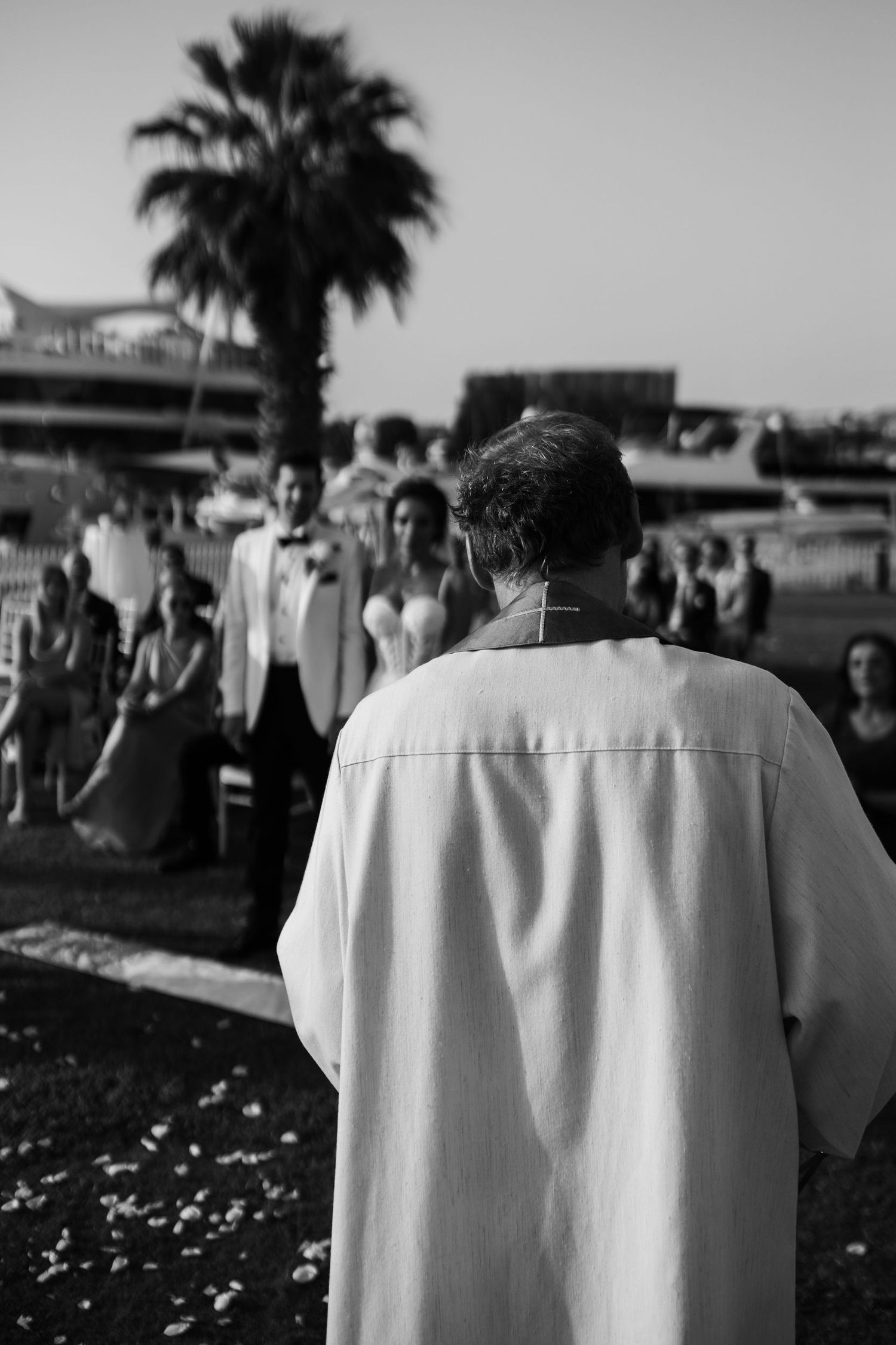 A black and white photograph showing people in white attire at an outdoor gathering.